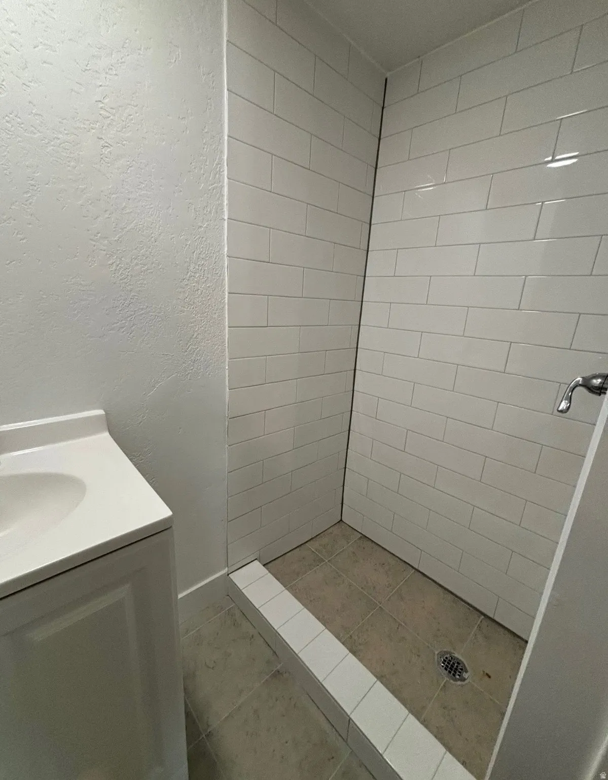 Walk-in shower featuring white subway tile walls and a contrasting tiled floor