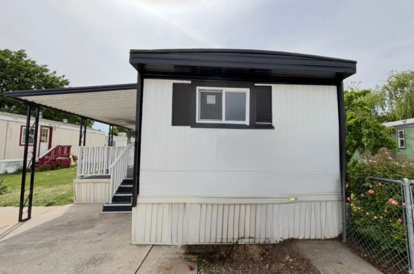 White exterior siding with dark trim and shutters, featuring a covered side entrance