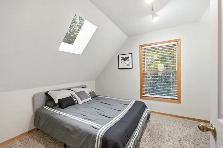 Carpeted room with a skylight and a window featuring wood trim