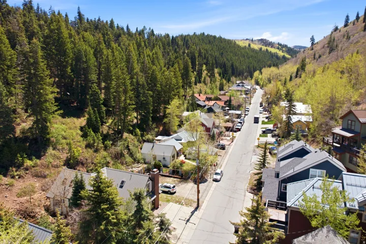 Neighborhood street with surrounding tree-covered hillsides and residential properties
