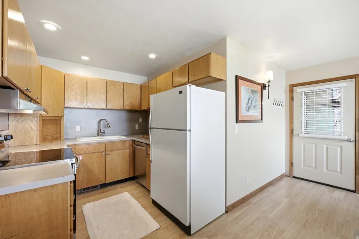 Functional kitchen featuring wood cabinetry, white appliances, recessed lighting, and wood-finish flooring