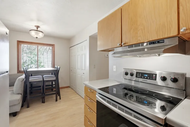 Kitchen area featuring light wood-finish flooring and a window with wood trim