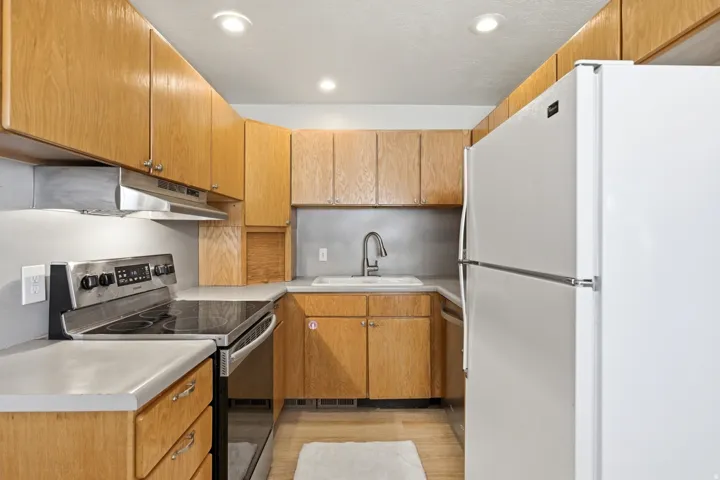 Kitchen featuring wood-finish cabinetry, light countertops, and a white refrigerator