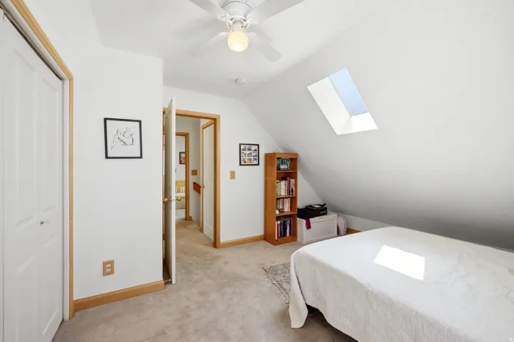 Attic bedroom featuring an angled ceiling, skylight, and wall-to-wall carpeting