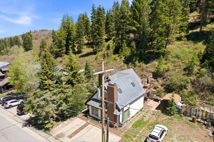 White-sided residence featuring a gray metal roof, multiple skylights, and a prominent brick chimney