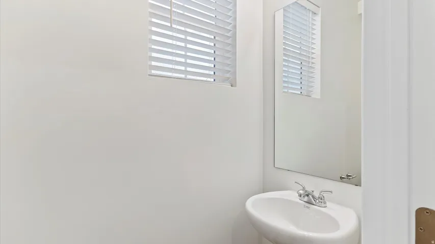 Pedestal sink with chrome faucet set against light-colored walls