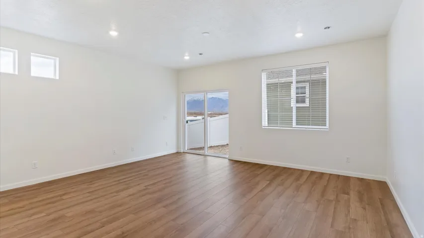 Spacious room featuring wood-finish flooring, recessed lighting, and a sliding glass door providing access to the exterior