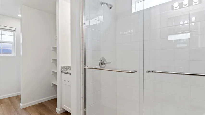 Shower enclosure with glass paneling and chrome hardware, featuring white subway tile surround and a chrome showerhead