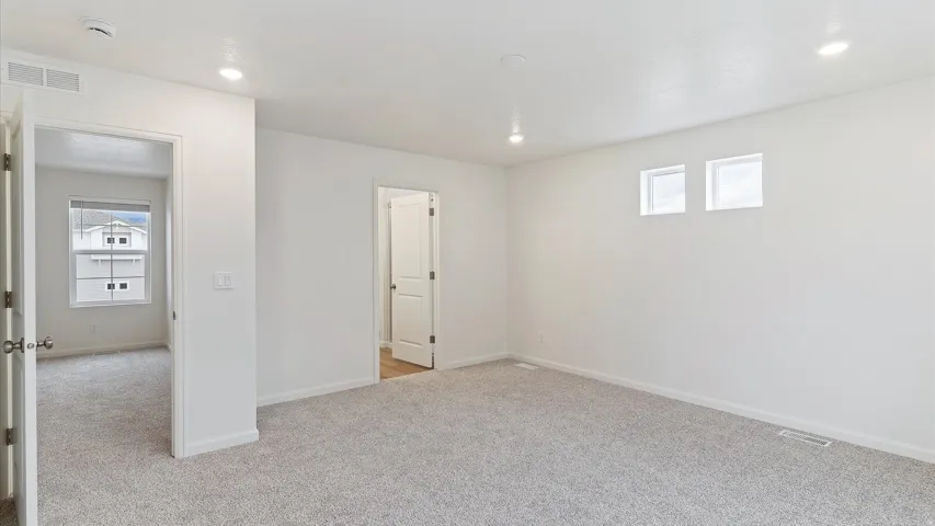 Spacious room featuring new carpet, white walls, recessed lighting, and two high-set windows