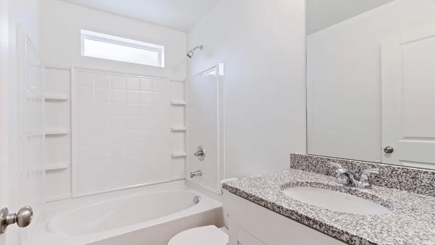 Bathroom featuring a white bathtub, tiled shower surround with built-in shelving, and a transom window