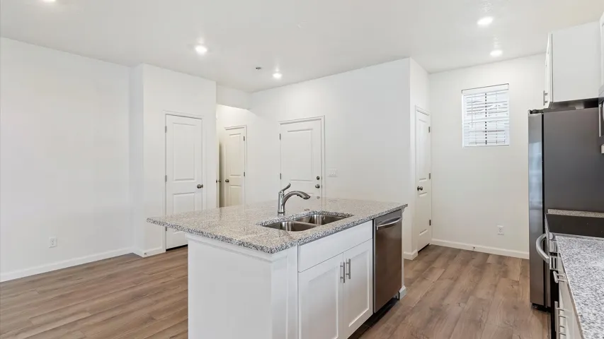 Kitchen featuring a central island with a double basin sink and a stone-finish countertop