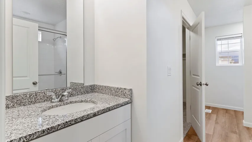 Bathroom vanity with a granite-finish countertop, undermount sink, and chrome faucet