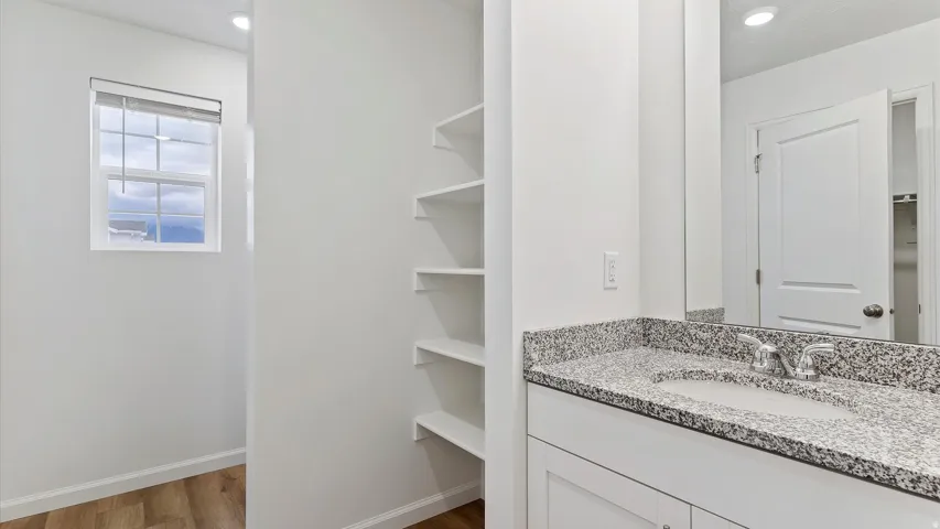 Vanity with a speckled countertop and integrated sink, chrome faucet, and white cabinetry