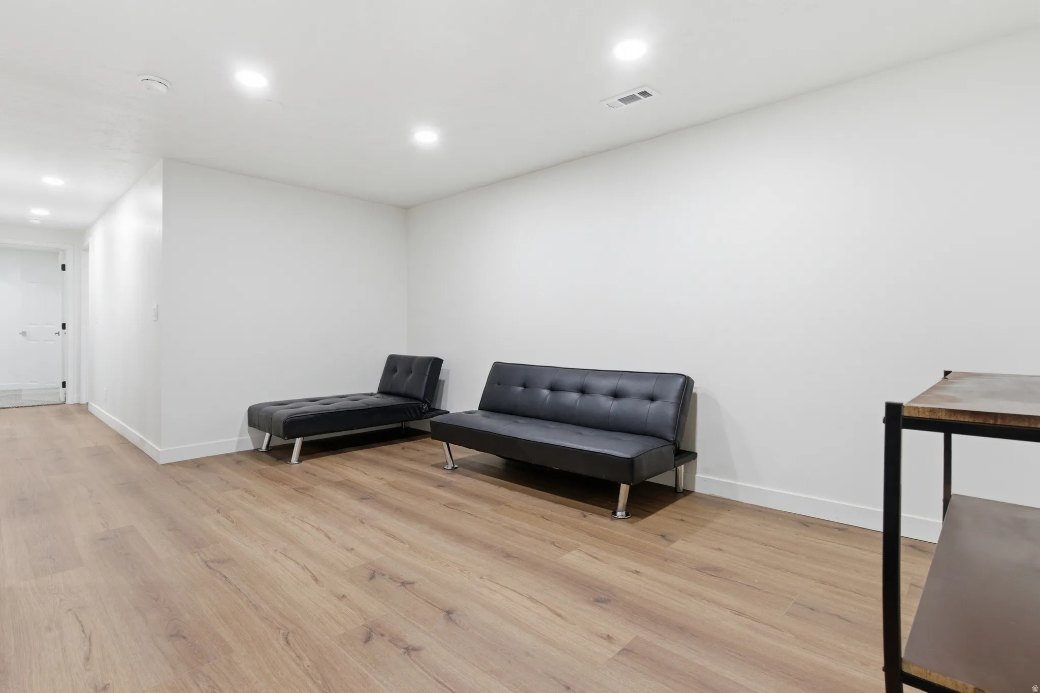Spacious room featuring wood-finish flooring, recessed lighting, and white baseboards