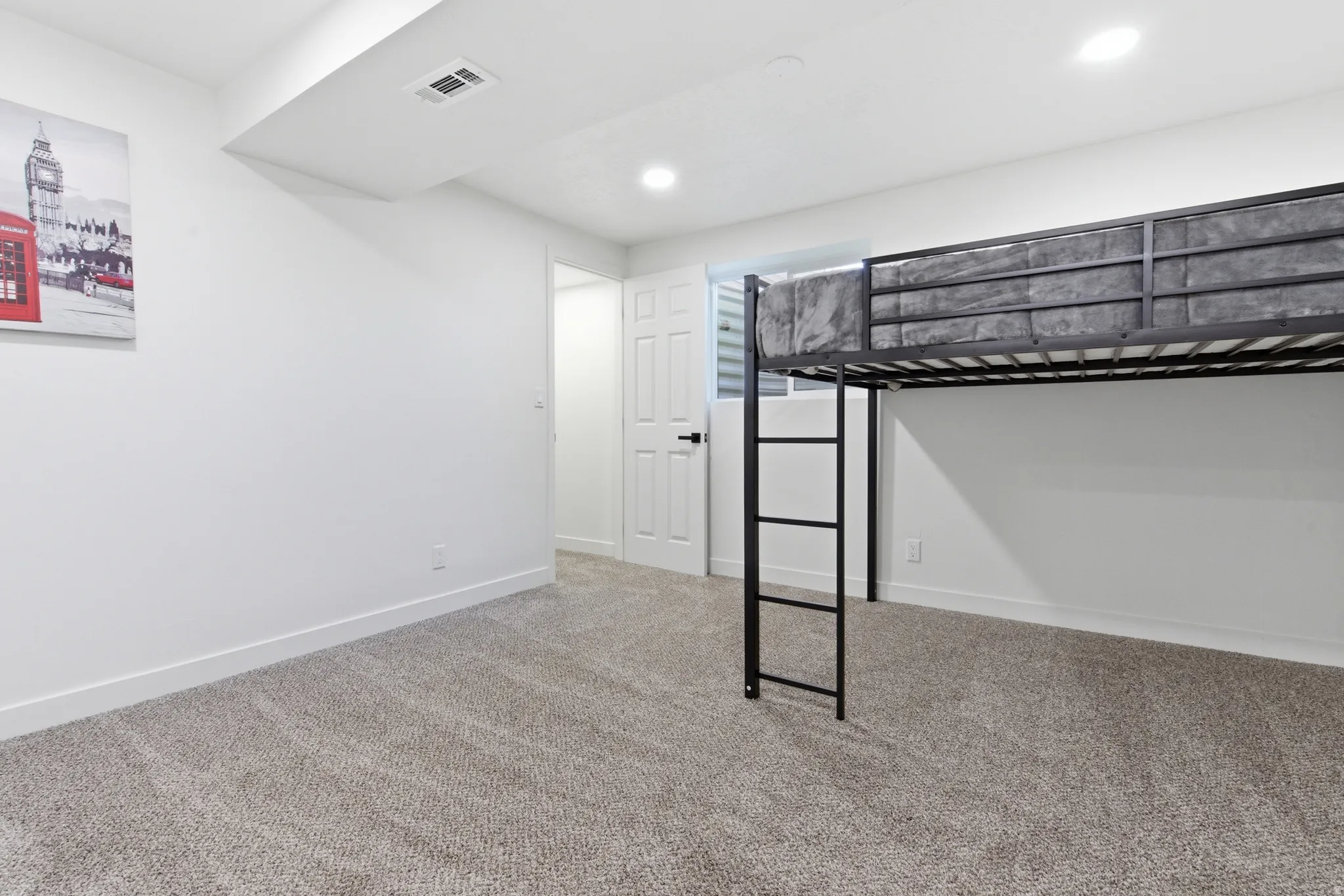 Carpeted room featuring white walls, recessed lighting, and a white interior door with black hardware