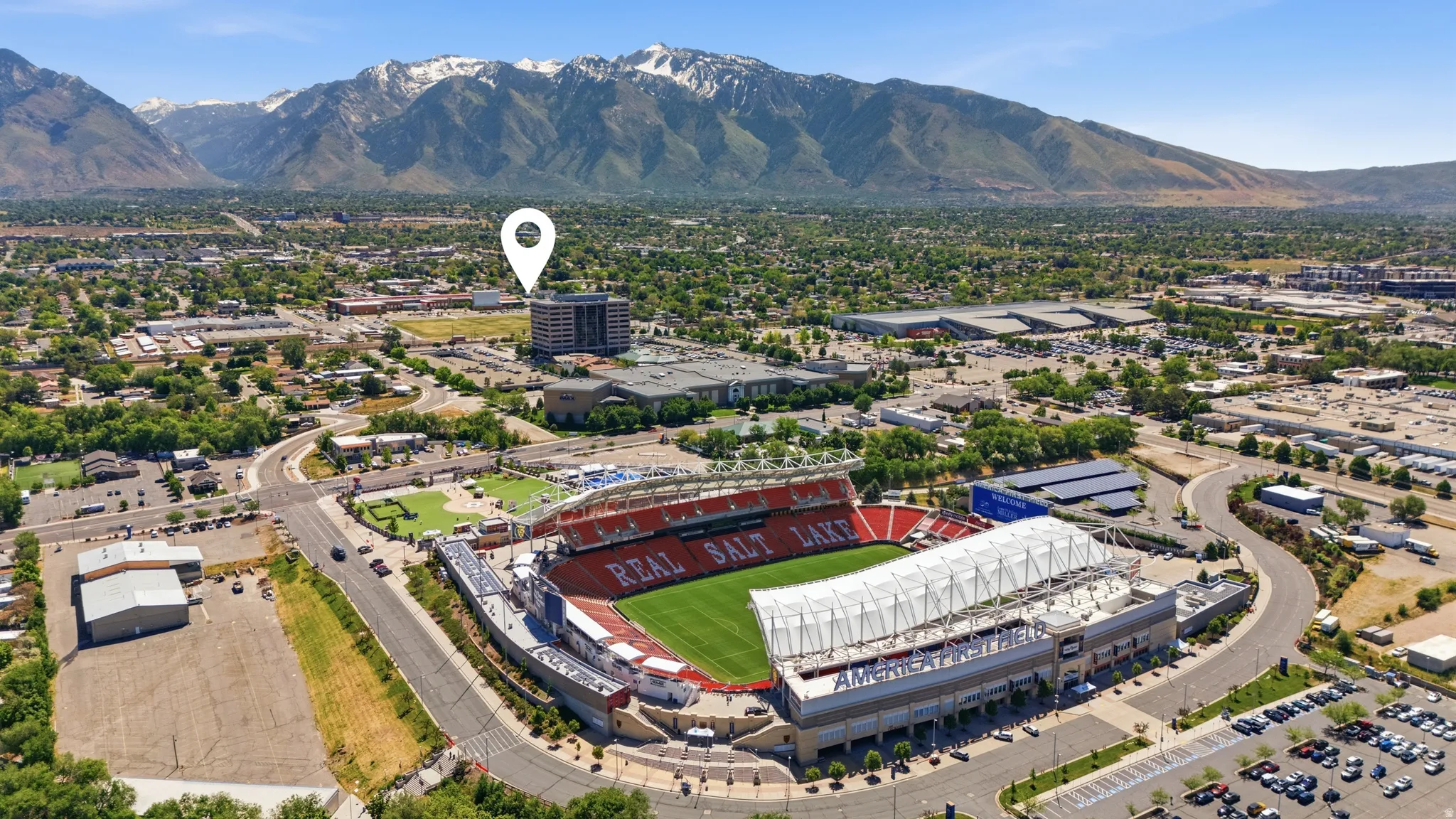 Aerial perspective showcasing a large stadium complex surrounded by commercial structures, residential areas, and expansive parking facilities