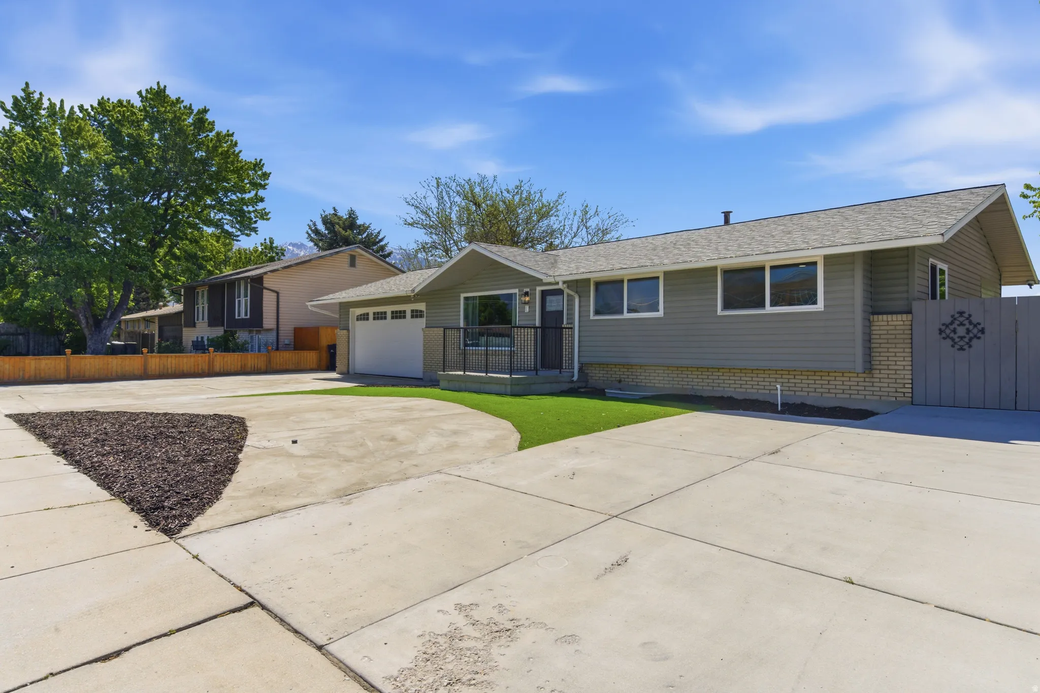 Front exterior with gray siding, a white garage door, and a concrete driveway