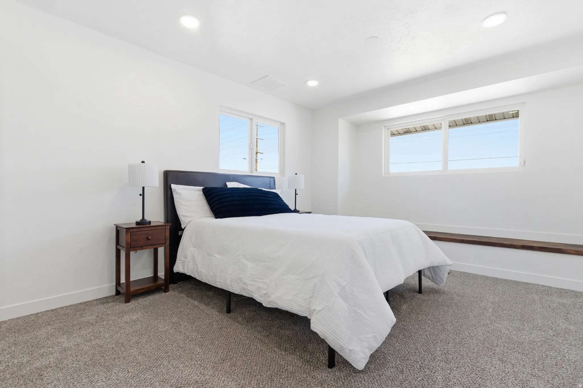 Bedroom featuring light gray carpeting, crisp white walls, recessed ceiling lighting, and multiple windows for natural light