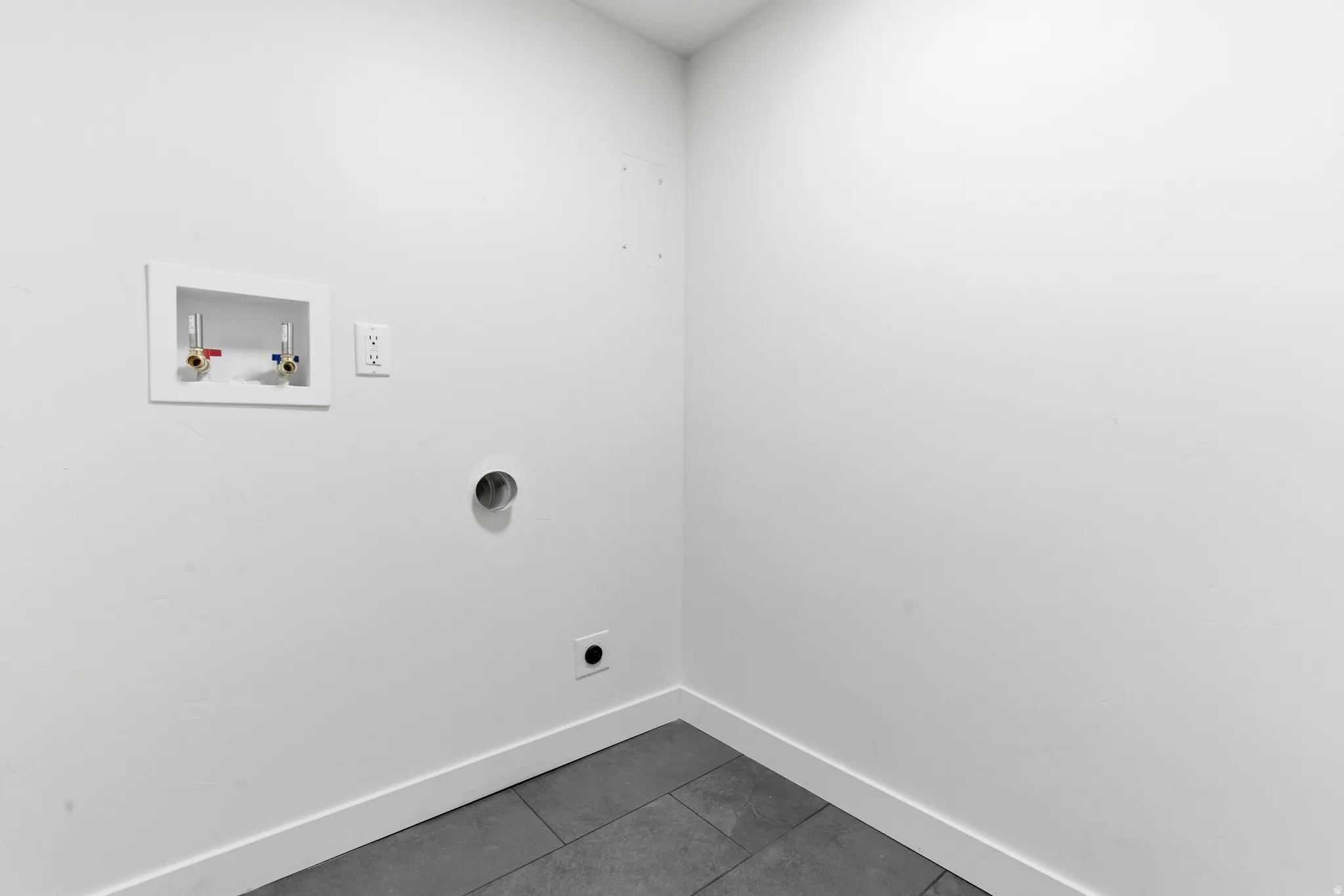 Dedicated utility space featuring a wall-mounted water supply box, electrical outlet, and vent connections