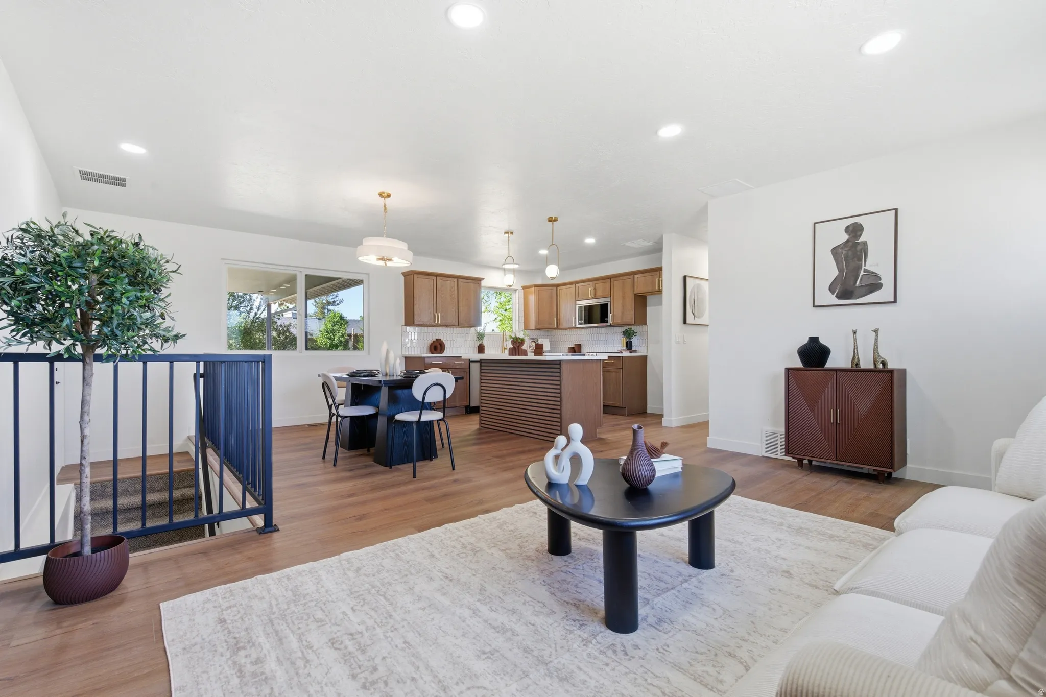 Open-concept living area with wood-finish flooring, white walls, and recessed lighting