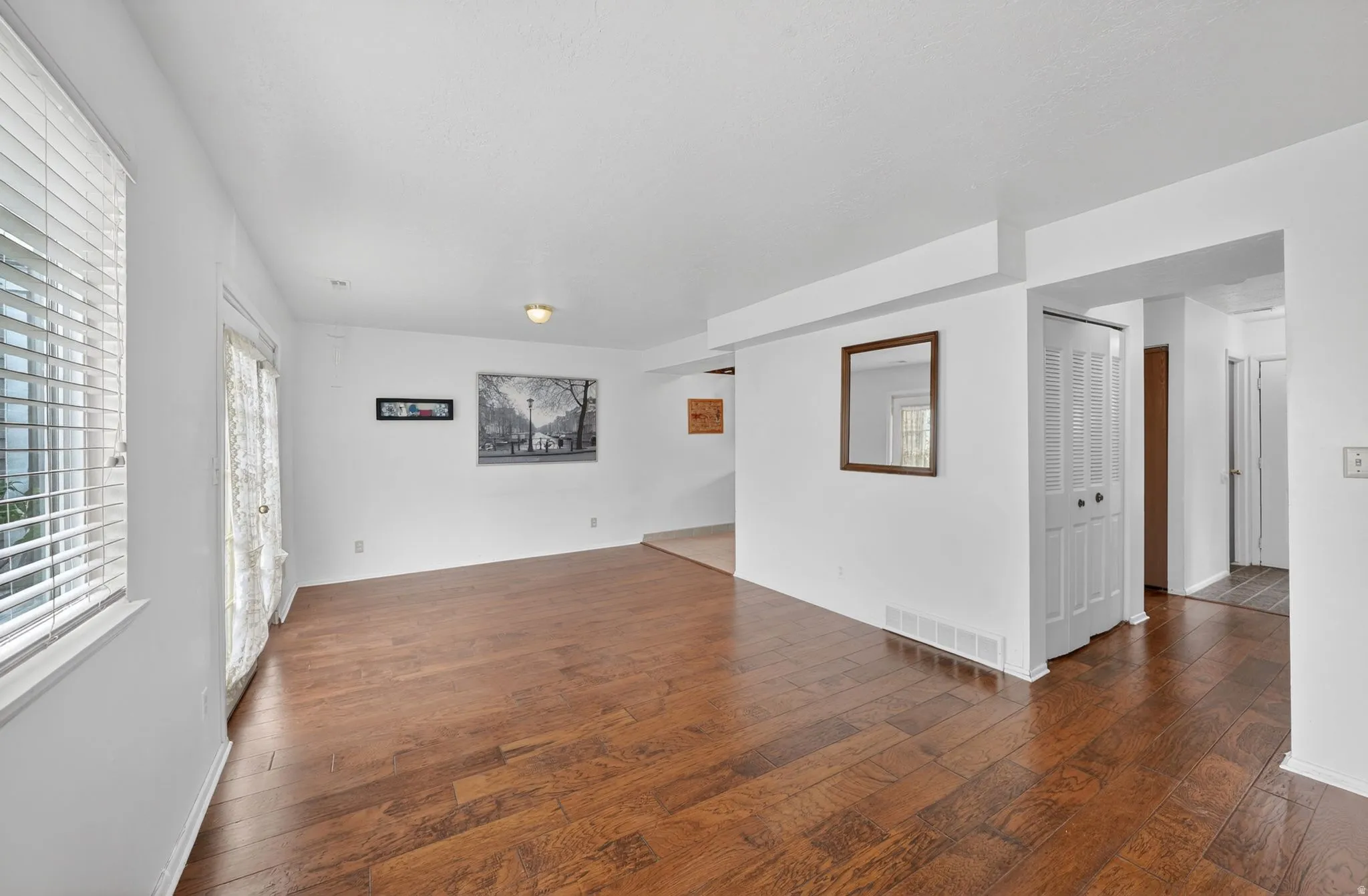 Spacious room featuring wood-finish flooring, white walls, and a recessed ceiling light