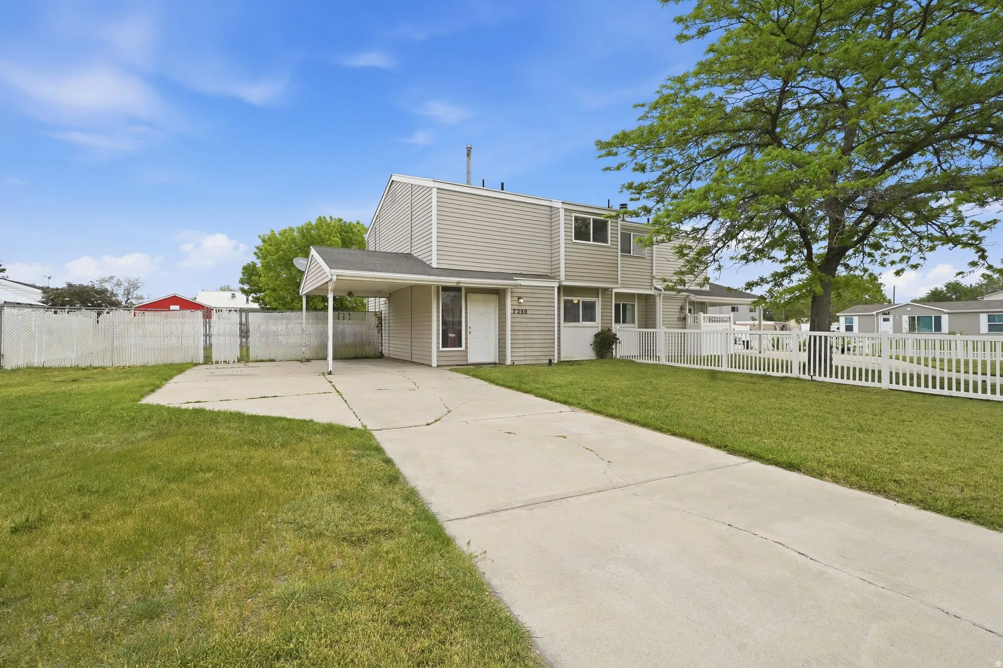 Two-story residence featuring light gray siding and a covered carport