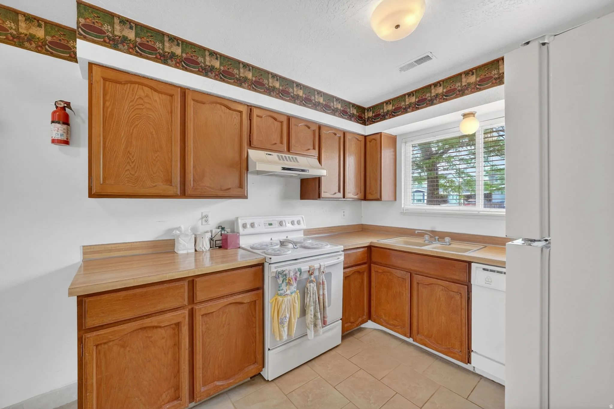 Kitchen featuring wood-finish cabinetry, a white electric range, and a double-basin sink