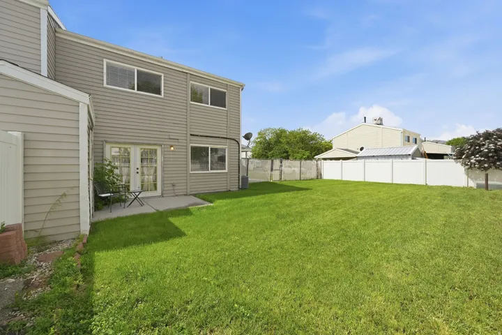 Expansive green lawn with a white privacy fence