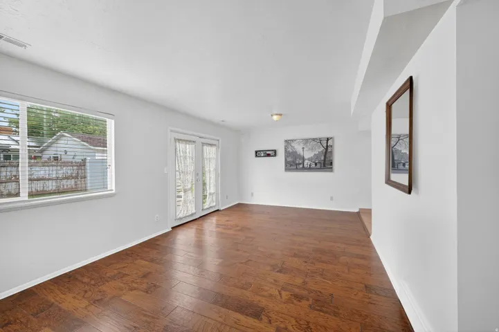 Spacious room featuring wood-finish flooring, white walls, and a large window