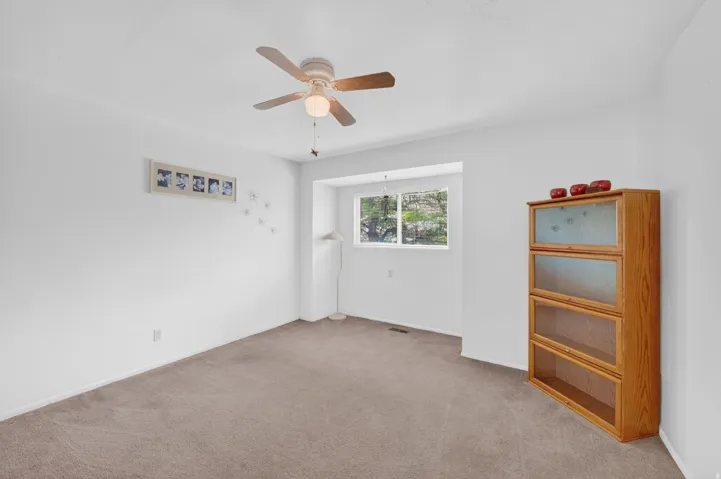 Carpeted interior space with a ceiling fan light fixture