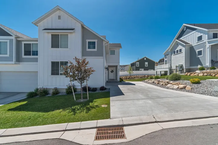 Board and batten facade, attached garage, concrete driveway, landscaped front yard, and rock garden