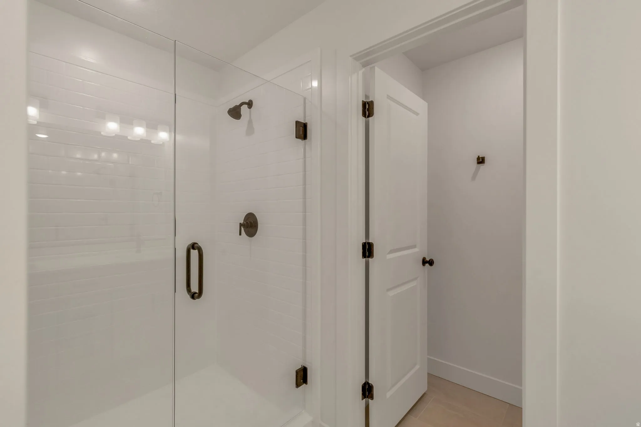 Walk-in shower featuring subway tile surround, clear glass enclosure, and bronze fixtures