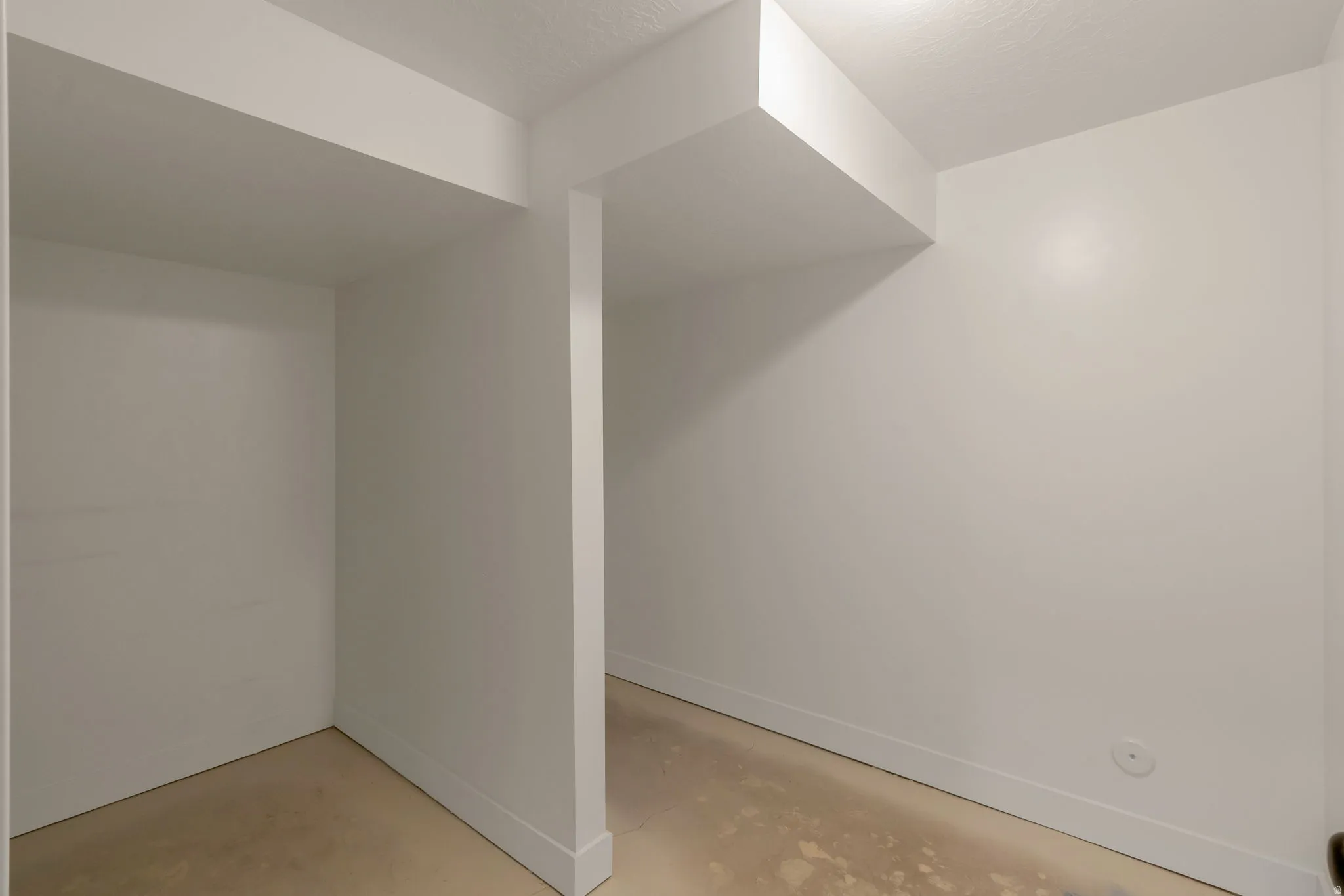 Storage room in basement. White painted interior walls with white baseboards, textured ceiling, and recessed ceiling lighting