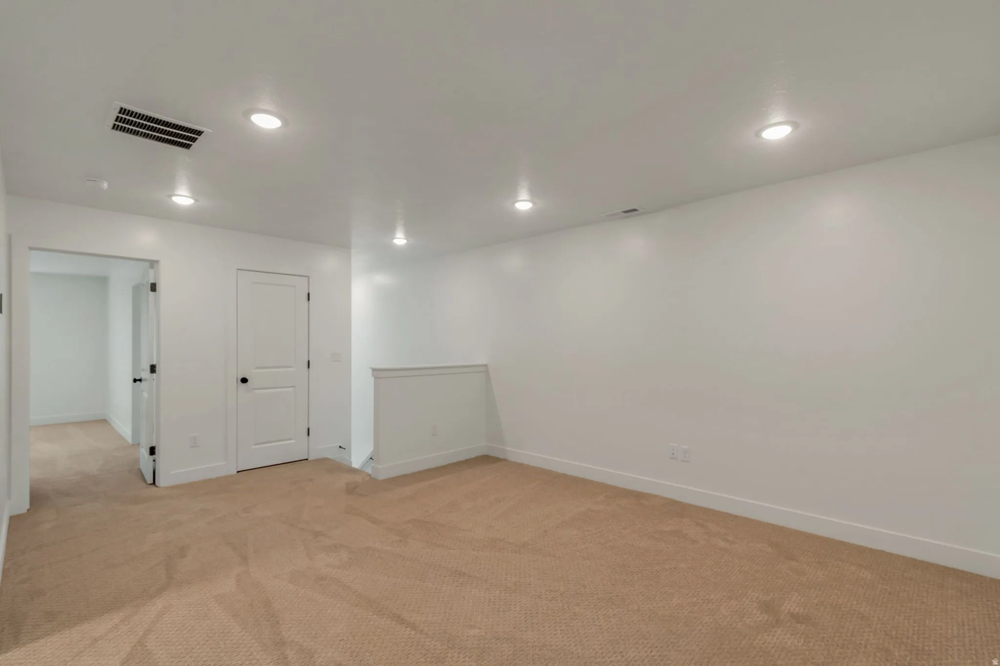 Spacious open area on upper floor, perfect for office, gym or play area. Featuring neutral carpeting, white painted walls, and recessed lighting