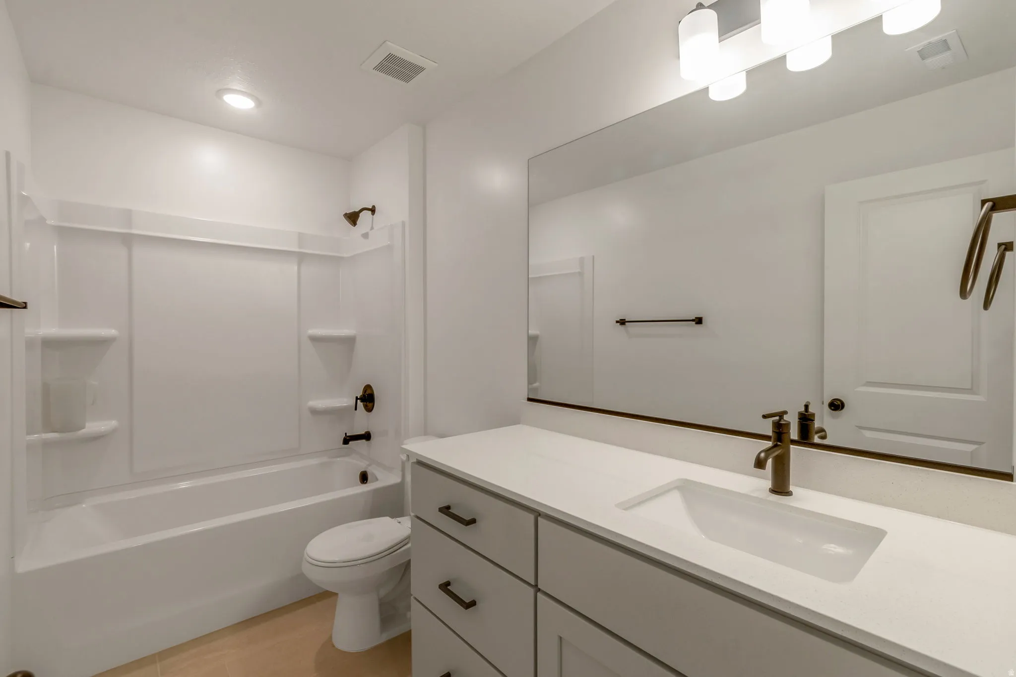 Bathroom featuring a single vanity with an integrated sink and white countertop, bronze-finish fixtures, a full-width mirror, and a white tub/shower combination