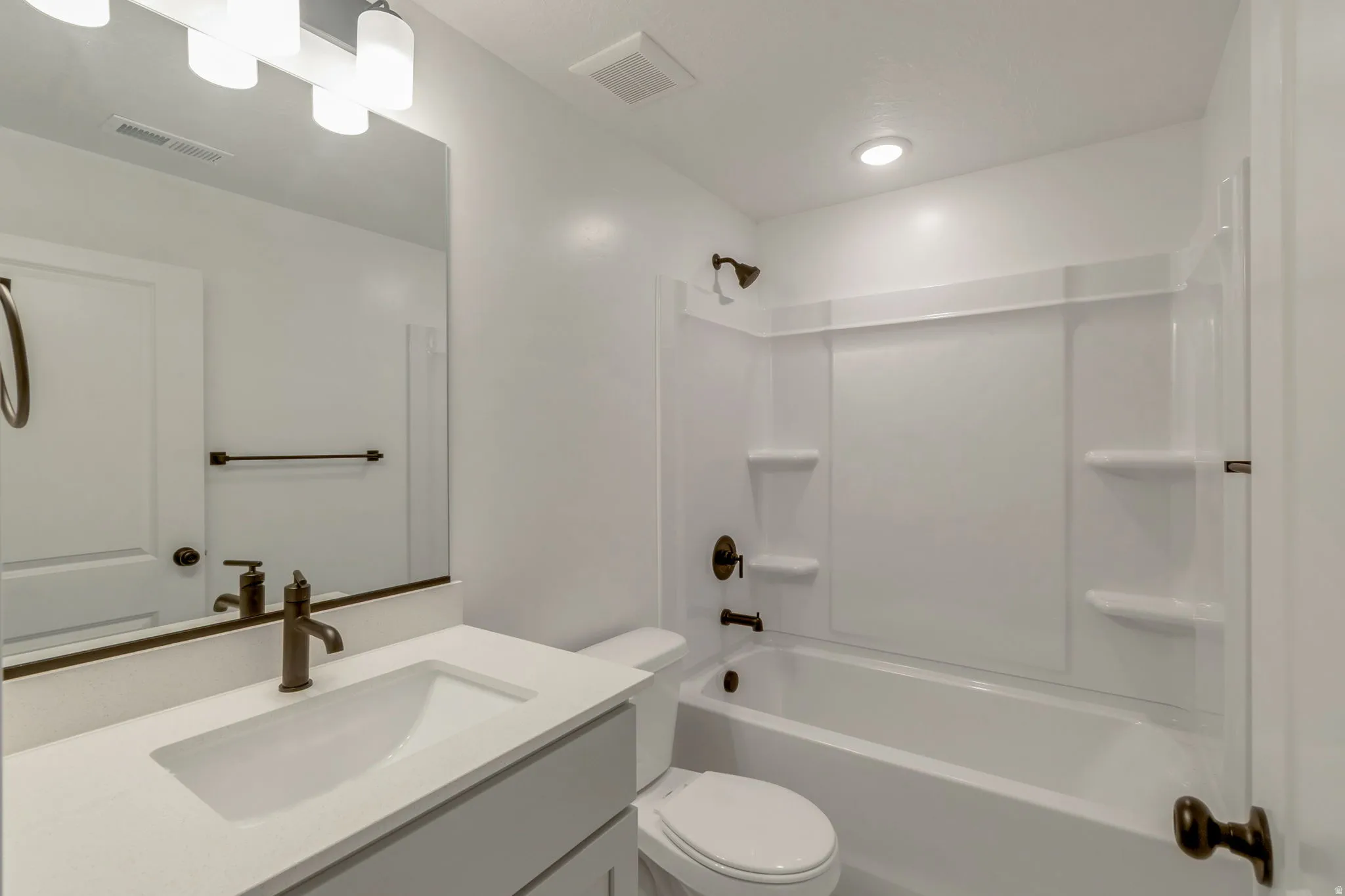 Bathroom featuring a white bathtub with integrated shower, a vanity with a rectangular undermount sink, solid surface countertop, and bronze-finish fixtures