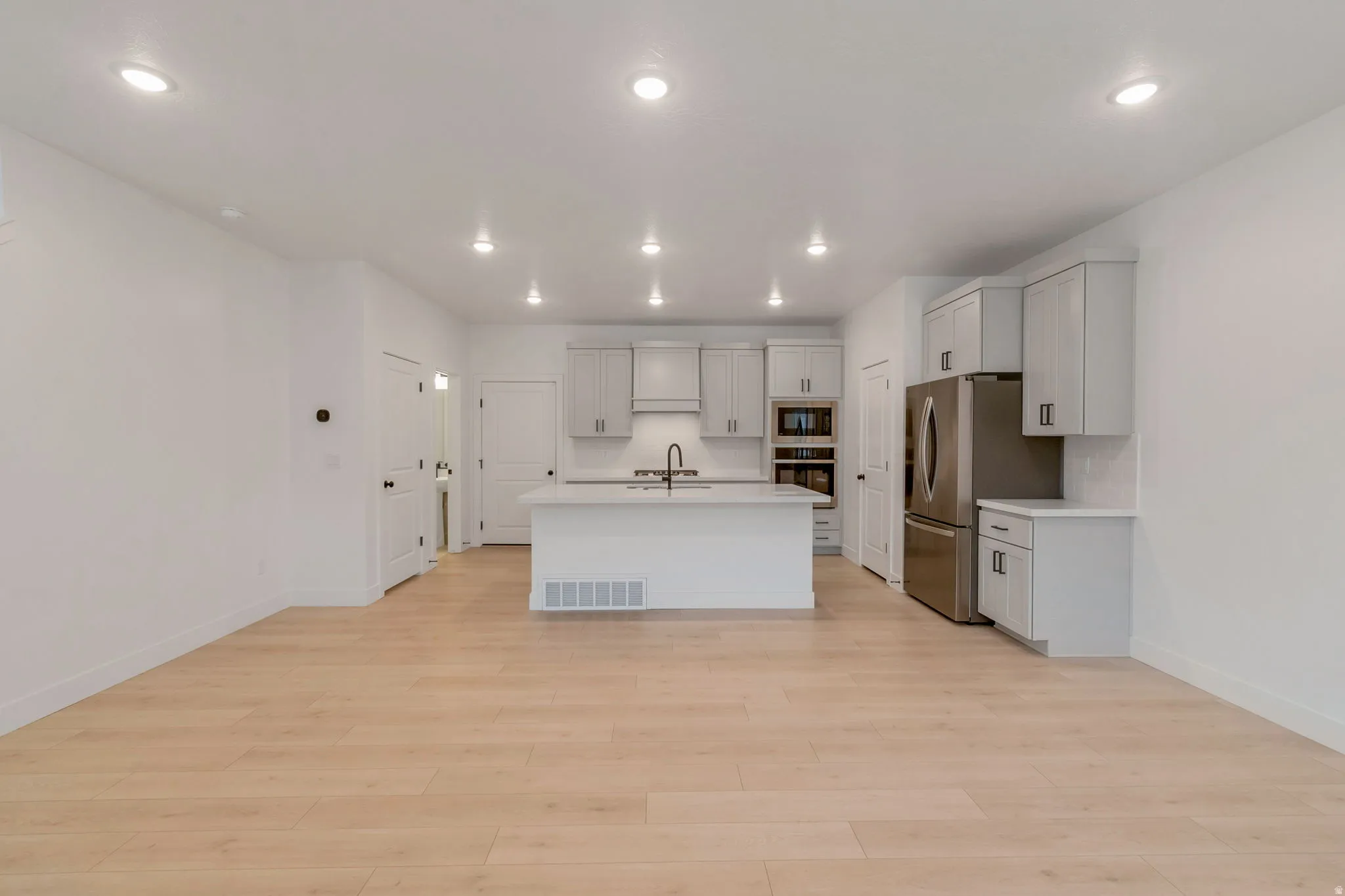 Open-concept living space featuring wood-finish flooring, recessed lighting, and a contemporary kitchen