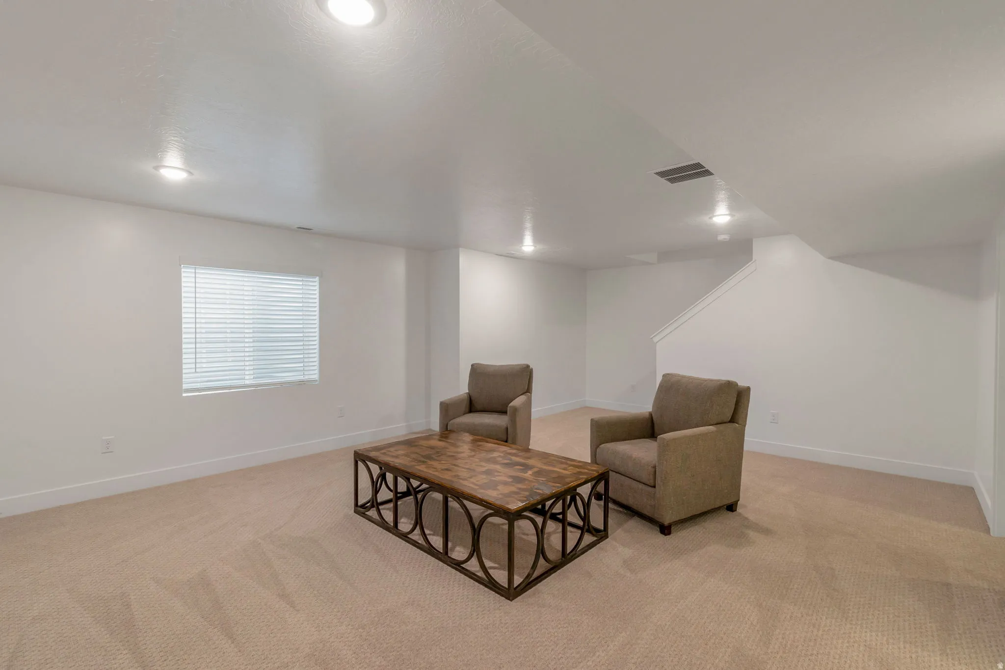 Spacious room with plush carpeting, recessed lighting, a window with blinds, and white baseboards