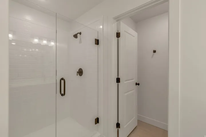 Walk-in shower featuring subway tile surround, clear glass enclosure, and bronze fixtures