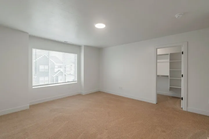 Carpeted room with a large window featuring horizontal blinds