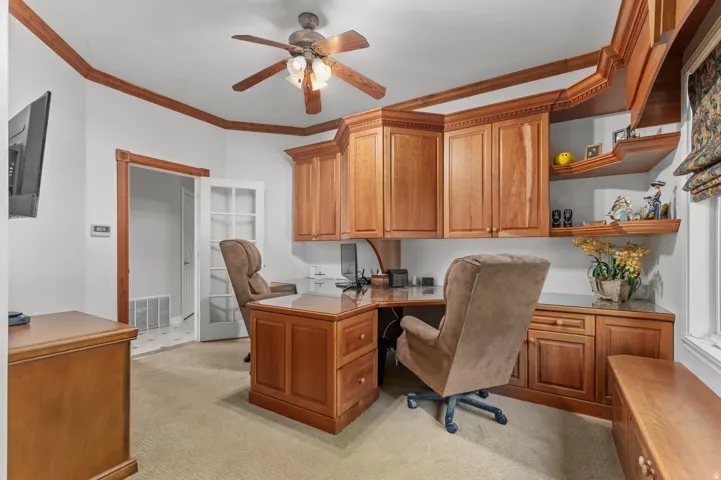 Built-in wood cabinetry with integrated desk space, complemented by a wood-finish ceiling fan and coordinating wood trim