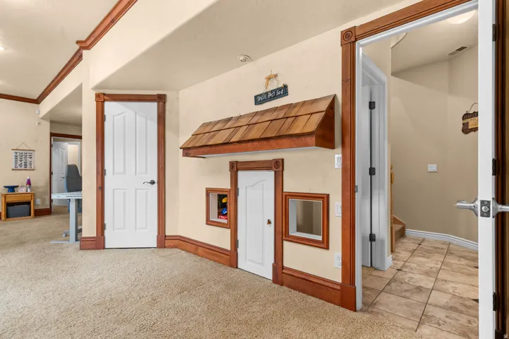 Custom built-in playhouse featuring a shingled roof, arched doorway, and two framed window openings