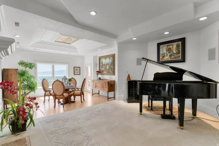 Carpeted flooring contrasting with wood-finish flooring, recessed lighting, white walls, and a multi-tiered tray ceiling with a decorative inset