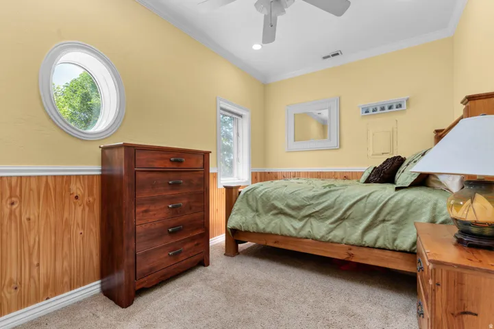 Bedroom featuring a distinctive oval window, wood paneling, crown molding, a ceiling fan, and recessed lighting