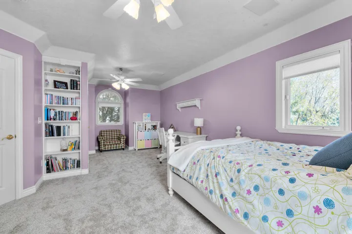 Spacious room featuring light lavender walls, plush grey carpeting, and white crown molding