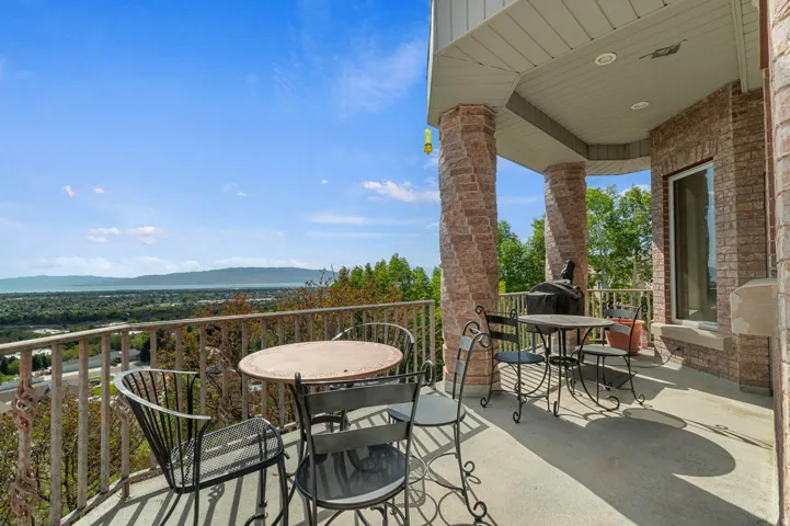 Spacious balcony featuring brick columns, a concrete surface, and a metal railing just off from the kitchen formal dining room