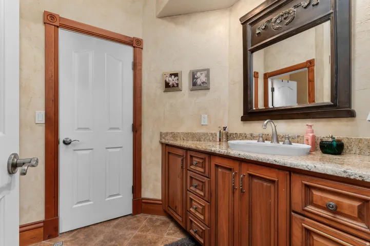 Bathroom vanity featuring a vessel sink, brushed nickel faucet, and a granite countertop