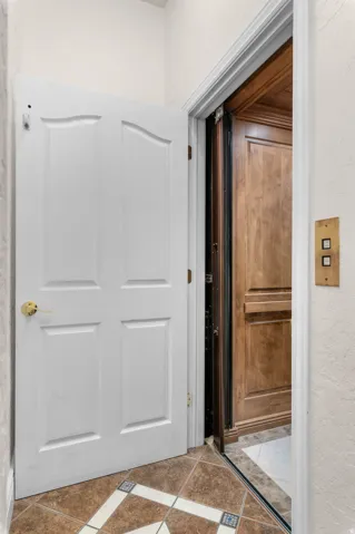 Interior elevator with a wood-paneled cabin, brass call buttons, and a complementary tile floor with decorative accents.  Located on all 4 floors