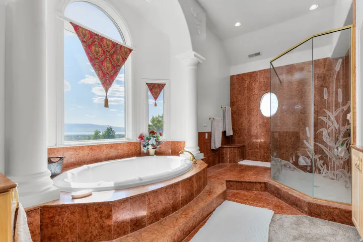 Luxurious soaking tub with expansive arched window, accented by decorative column