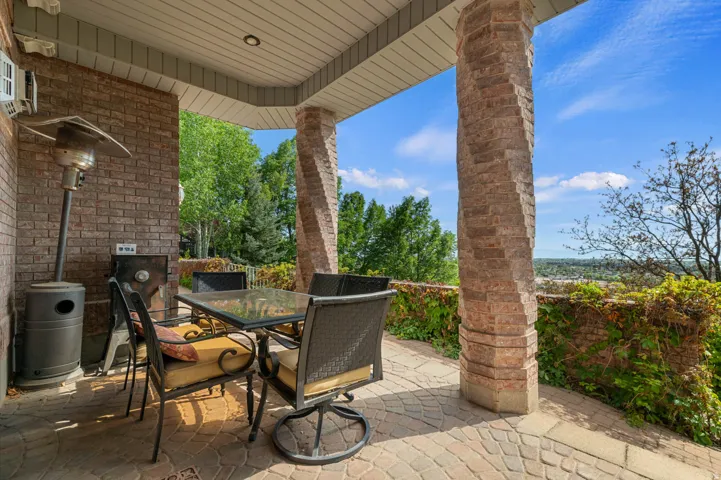 Covered patio featuring a brick wall, unique stone-clad columns, and a patterned paver floor.  Located just outside the french doors.